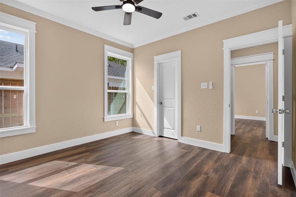 Wood-finish flooring, crisp white door and window casing, multi-pane windows, and a ceiling fan with integrated light fixture