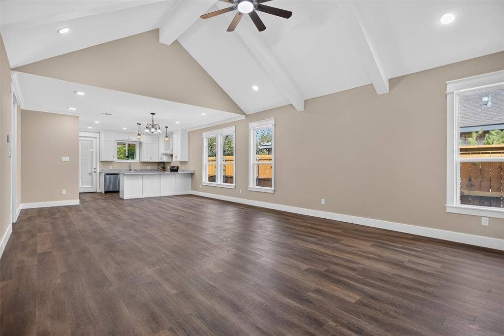 Vaulted ceilings with exposed beams, wood-finish flooring, recessed lighting, white kitchen cabinetry, and an integrated kitchen island