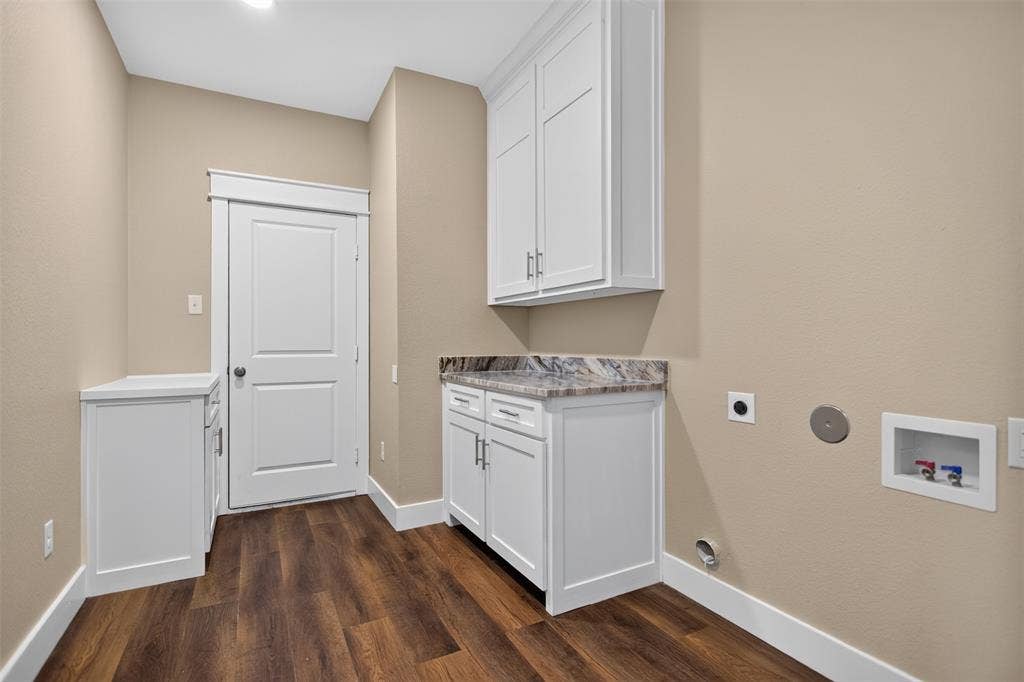 Utility room featuring wood-finish flooring, white shaker-style cabinetry, patterned stone-finish countertops, and matching wall-mounted storage cabinets