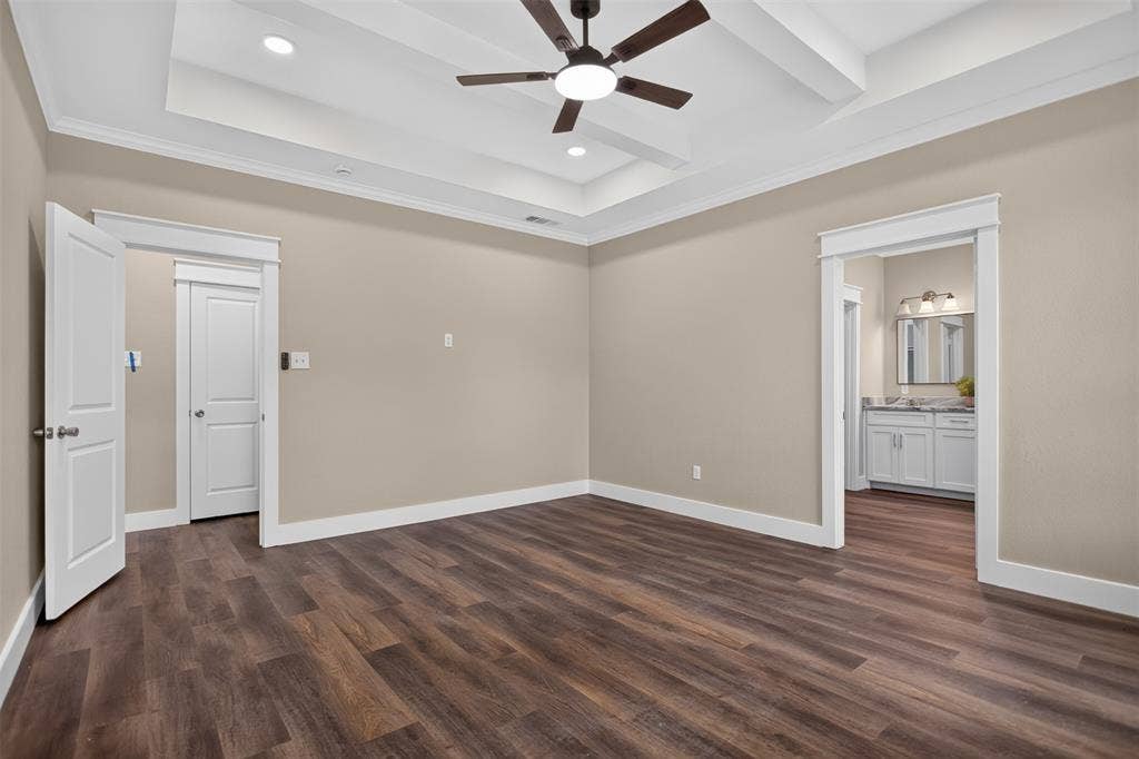 Tray ceiling with recessed lighting and a central ceiling fan, wood-finish flooring, and white paneled interior doors