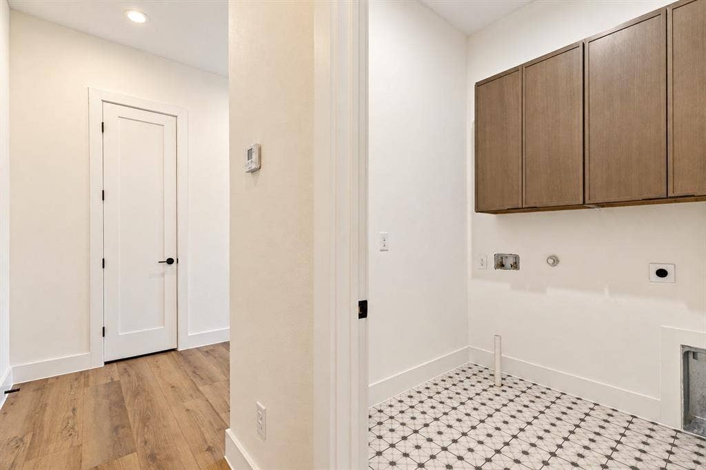 903 Bayonne Street, Dallas, TX 75212 Utility space featuring patterned floor tile, wood-finish upper cabinetry, and a clean white color palette