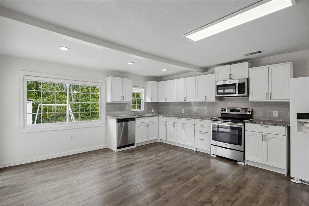 2245 County Road 337, McKinney, TX 75071 Kitchen featuring white shaker-style cabinetry, stone-finish countertops, subway tile backsplash, stainless steel appliances, and wood-finish flooring