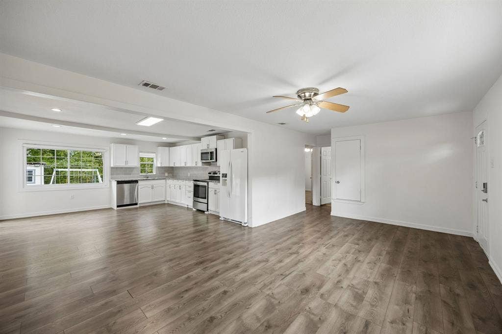 2245 County Road 337, McKinney, TX 75071 Open-concept interior featuring wood-finish flooring, white cabinetry, stainless steel appliances, and a ceiling fan with integrated lighting