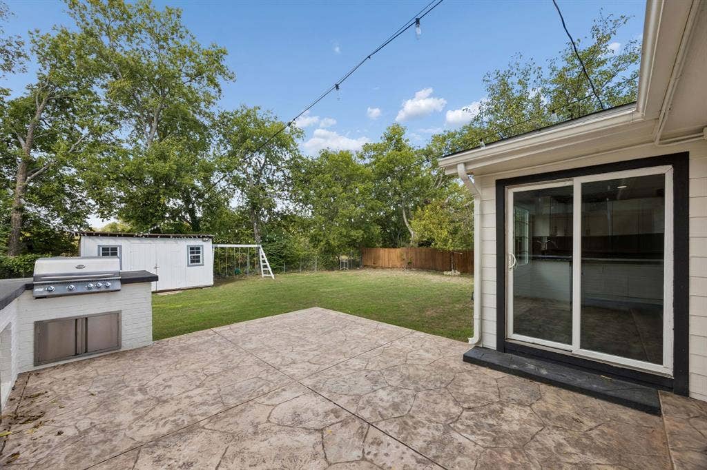 2245 County Road 337, McKinney, TX 75071 Stamped concrete patio featuring a built-in outdoor kitchen with a stainless steel grill, a fenced backyard, and a detached storage structure