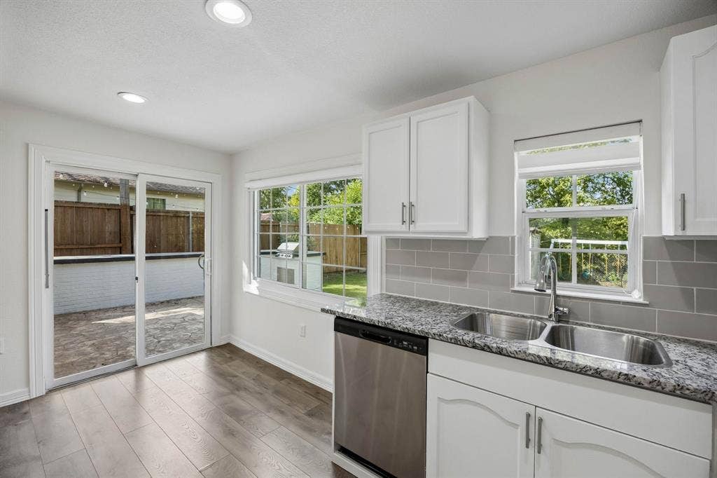 2245 County Road 337, McKinney, TX 75071 Kitchen featuring white cabinetry, stone-finish countertops, stainless steel dual-basin sink with gooseneck faucet, gray tile backsplash, and wood-finish flooring