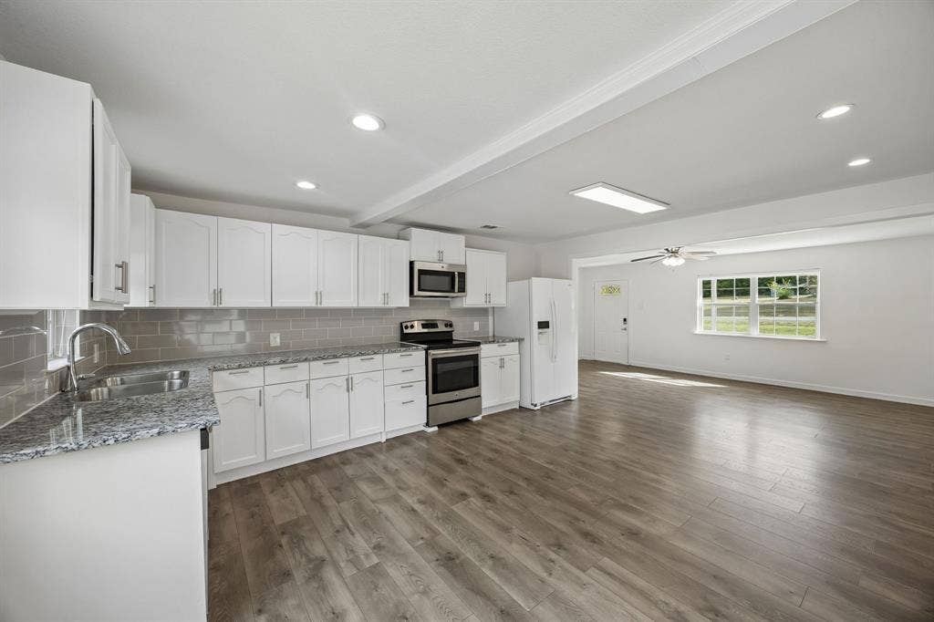 2245 County Road 337, McKinney, TX 75071 Kitchen featuring white shaker-style cabinetry, stone-finish countertops, subway tile backsplash, stainless steel appliances, and wood-finish flooring
