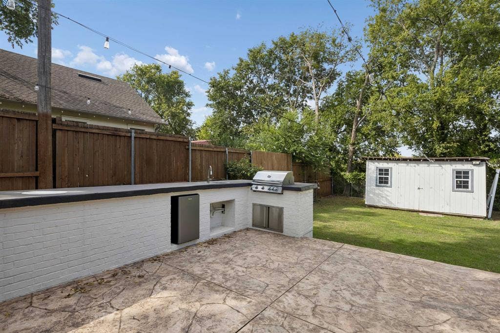 2245 County Road 337, McKinney, TX 75071 Outdoor kitchen featuring a painted brick base, stone countertop, stainless steel grill, under-counter refrigeration, and sink