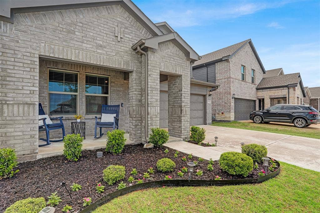 View of front of house featuring stone siding, concrete driveway, an attached garage, and brick siding