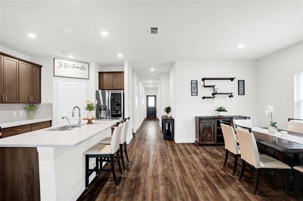 Kitchen featuring dark brown cabinetry, dark wood finished floors, recessed lighting, a breakfast bar, and backsplash
