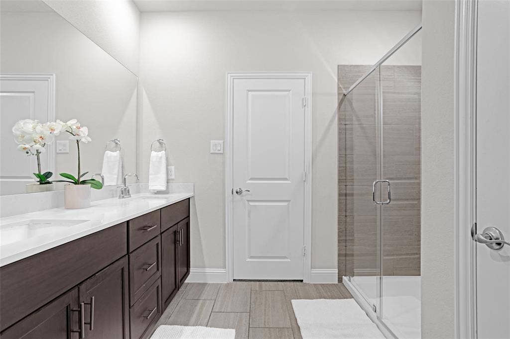 Full bath featuring a shower stall, double vanity, and wood tiled floors