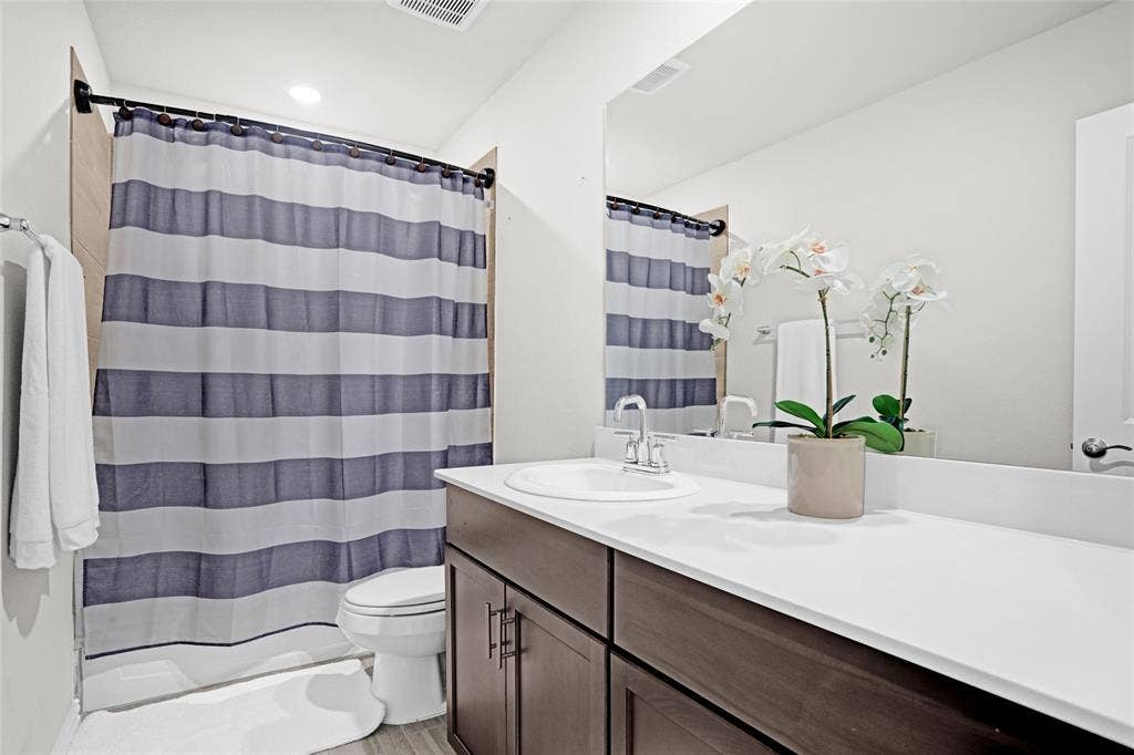 Bathroom with vanity, shower / bath combo, and recessed lighting