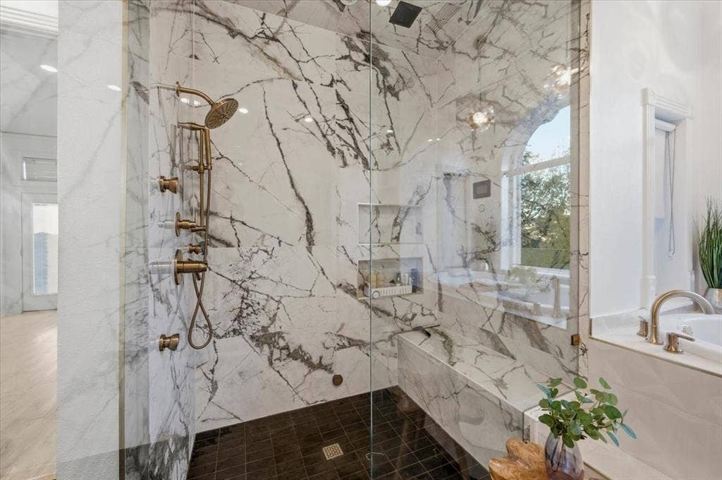 2945 Emerald Sound Drive, Cedar Hill, TX 75104 Walk-in shower featuring floor-to-ceiling stone-patterned tile, integrated wall niche, built-in stone bench, and antique-finish hardware with a rainfall showerhead