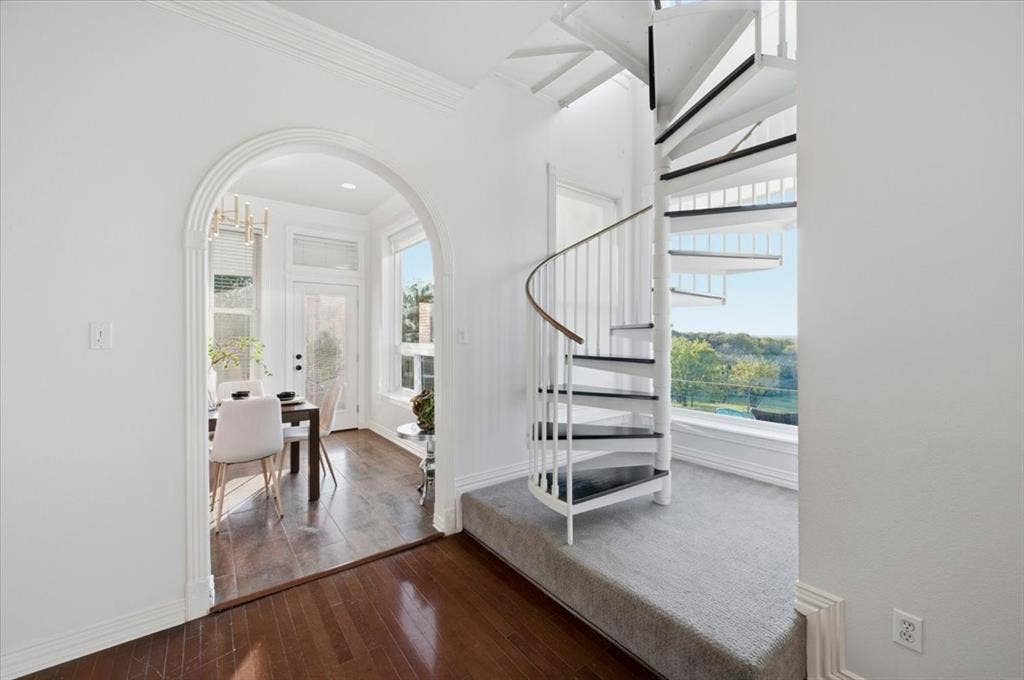 2945 Emerald Sound Drive, Cedar Hill, TX 75104 White metal spiral staircase featuring a wood handrail, architectural arched doorway, and wood-finish flooring
