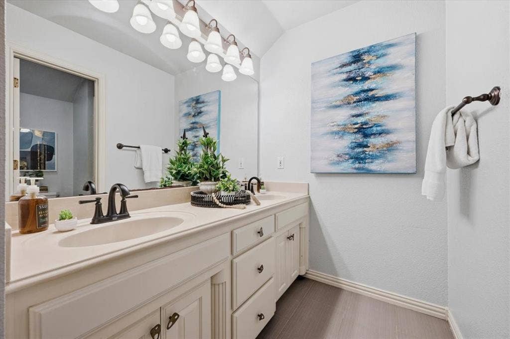 2945 Emerald Sound Drive, Cedar Hill, TX 75104 Double vanity featuring white cabinetry, dual integrated sinks with matte black faucets, an expansive wall-mounted mirror, and multi-light overhead vanity fixture