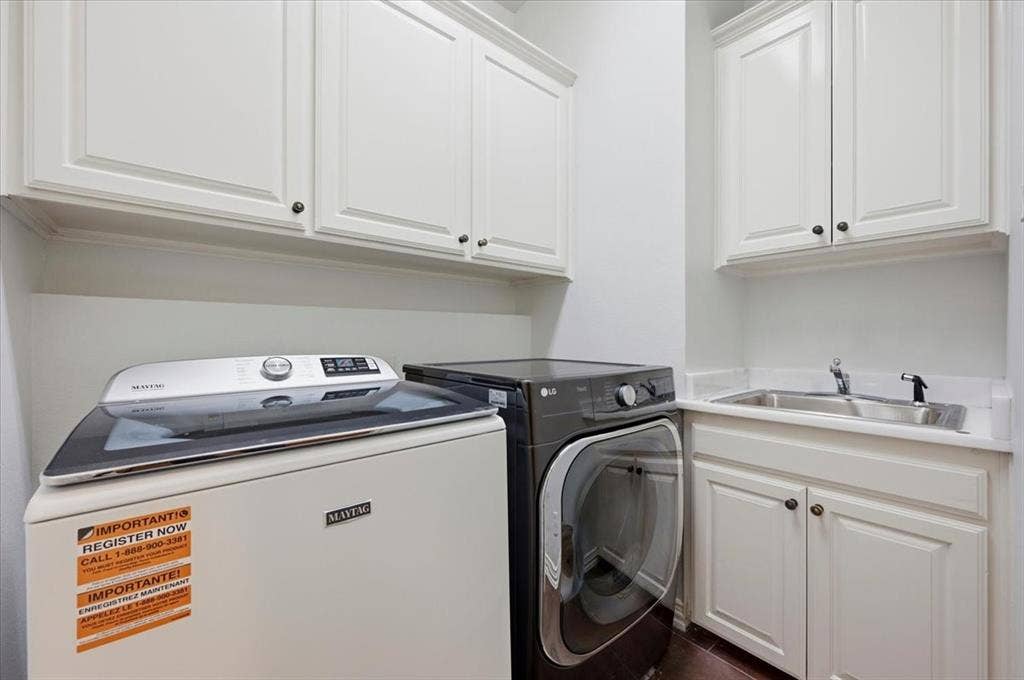 2945 Emerald Sound Drive, Cedar Hill, TX 75104 Dedicated laundry area featuring white shaker-style cabinetry, a drop-in stainless steel sink, and solid-surface countertops