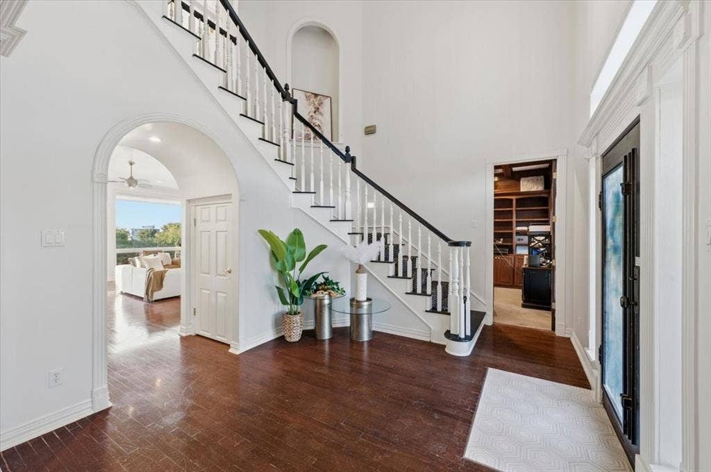 2945 Emerald Sound Drive, Cedar Hill, TX 75104 Foyer featuring wood-finish flooring, a staircase with decorative railings, arched architectural openings, an inset wall niche, and built-in cabinetry