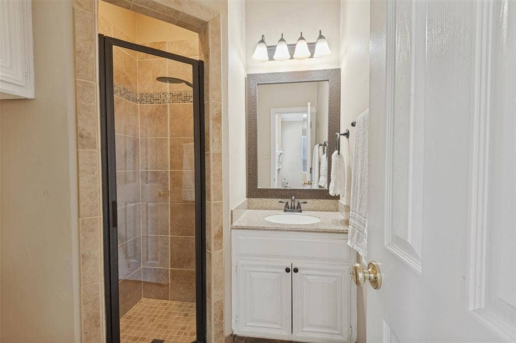 2704 Horsehead Crossing, Southlake, TX 76092 First floor bathroom featuring a vanity with a light-tone stone countertop, an integrated oval basin, and a framed mirror
