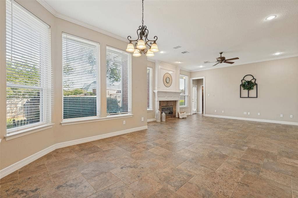 2704 Horsehead Crossing, Southlake, TX 76092 Open-concept room featuring large-format tile flooring, a stone-surround fireplace with a classic mantel, oversized windows with blinds, a multi-light chandelier, and a ceiling fan