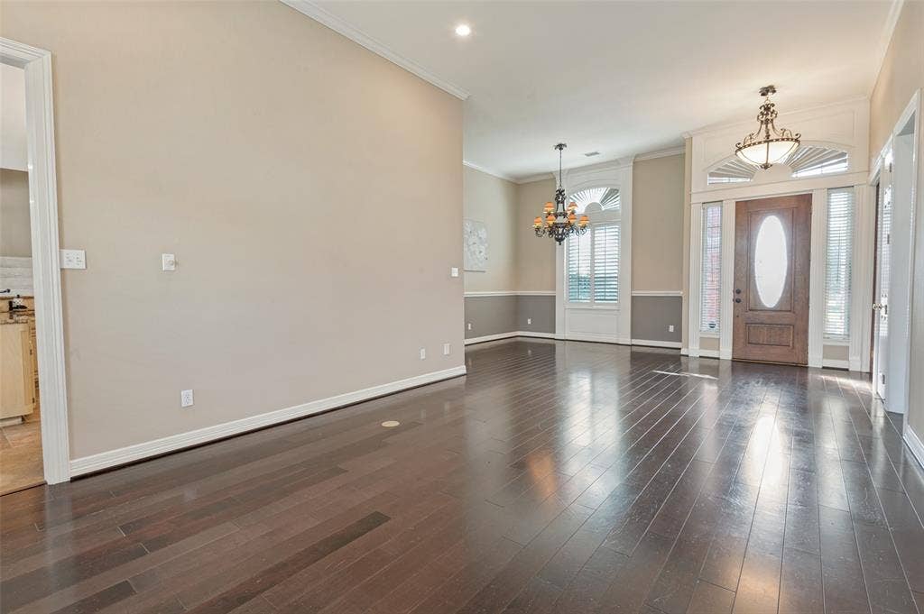 2704 Horsehead Crossing, Southlake, TX 76092 Dark wood-finish flooring, high ceilings with crown molding, decorative chandeliers, arched windows with plantation shutters, and a wood entry door with an oval glass insert and transom window
