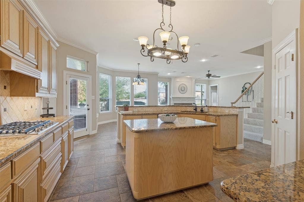 2704 Horsehead Crossing, Southlake, TX 76092 Kitchen featuring wood cabinetry, stone countertops, a central island, tile flooring, and decorative chandeliers