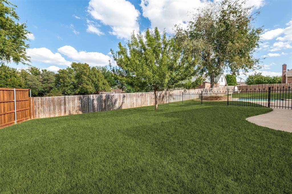 2704 Horsehead Crossing, Southlake, TX 76092 Backyard featuring a manicured lawn, wood privacy fencing, a metal perimeter fence, concrete hardscaping, and mature trees