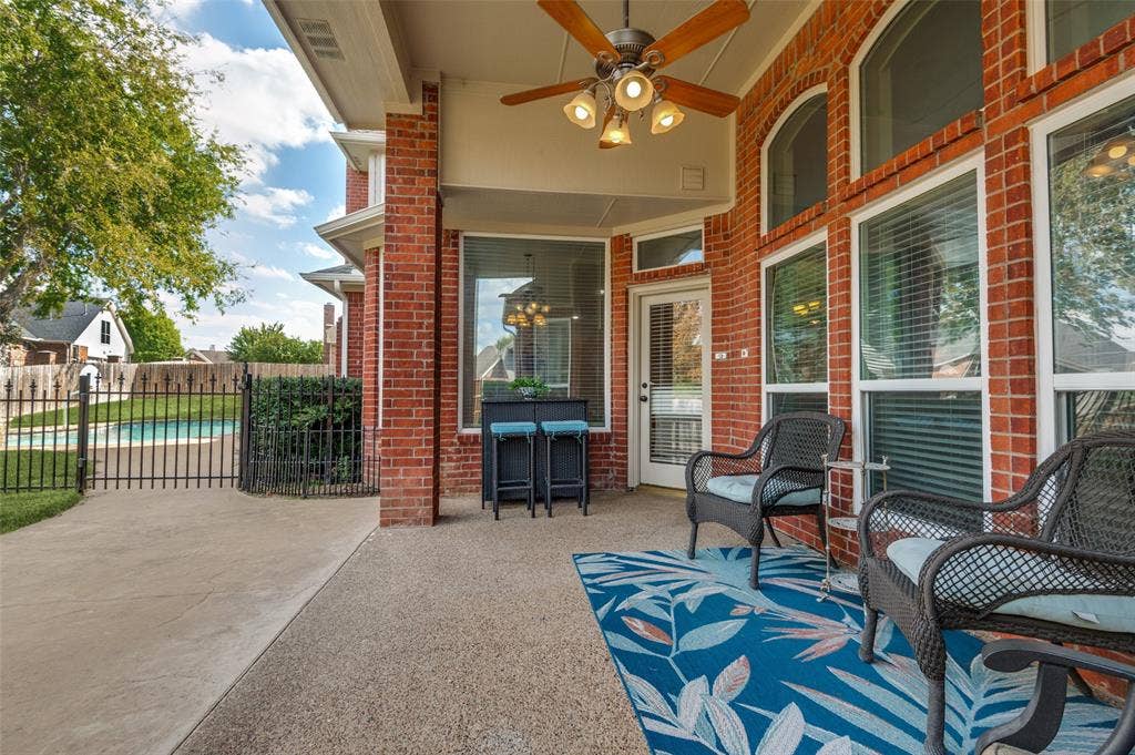 2704 Horsehead Crossing, Southlake, TX 76092 Covered patio featuring brick exterior walls, aggregate concrete flooring, an overhead ceiling fan with integrated lighting, and metal perimeter fencing