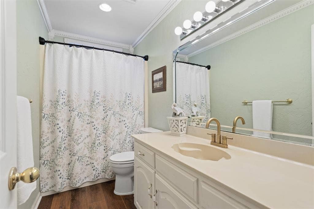White vanity with a neutral-toned countertop and an integrated sink, featuring a gold-finish faucet