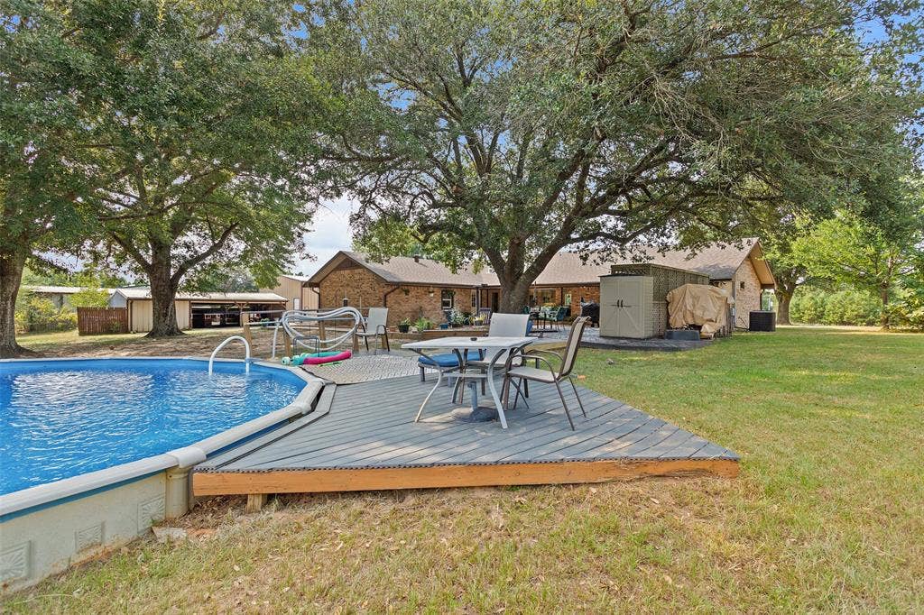 Outdoor space featuring an above-ground swimming pool, a wooden deck, and a grass lawn