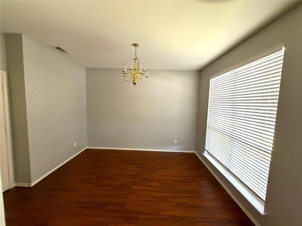 Recessed lighting, wood-finish flooring, large window with blinds, and a brass-tone chandelier