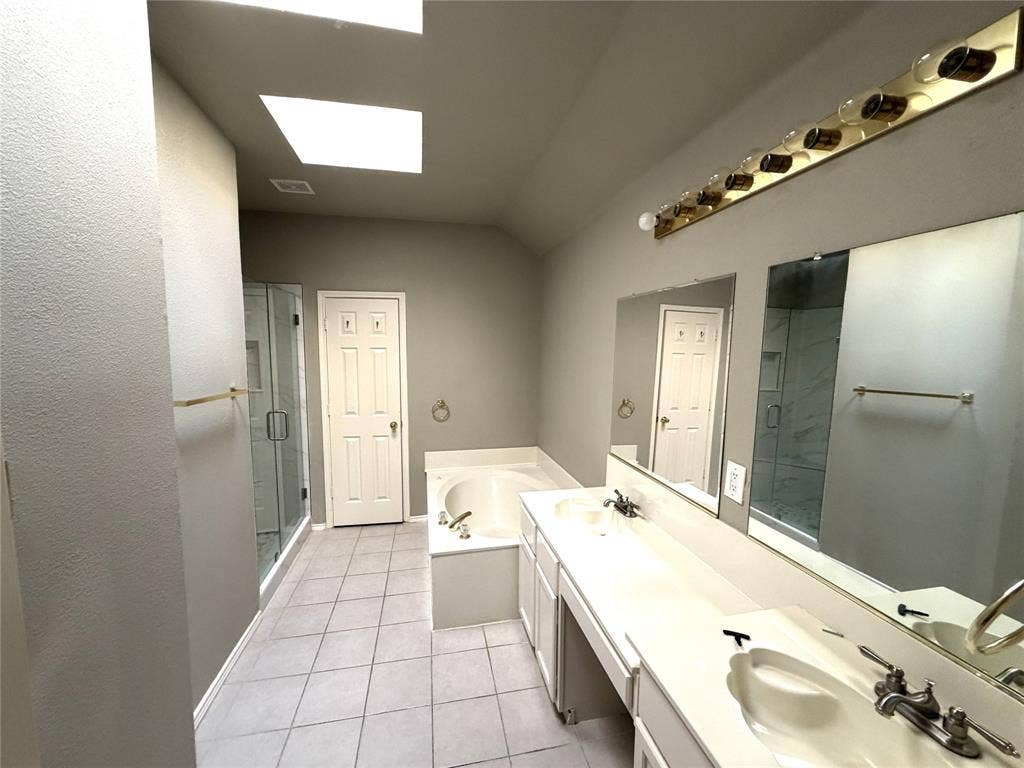 Dual skylights, large soaking tub, glass-enclosed shower, extensive vanity with dual sinks, and tile flooring