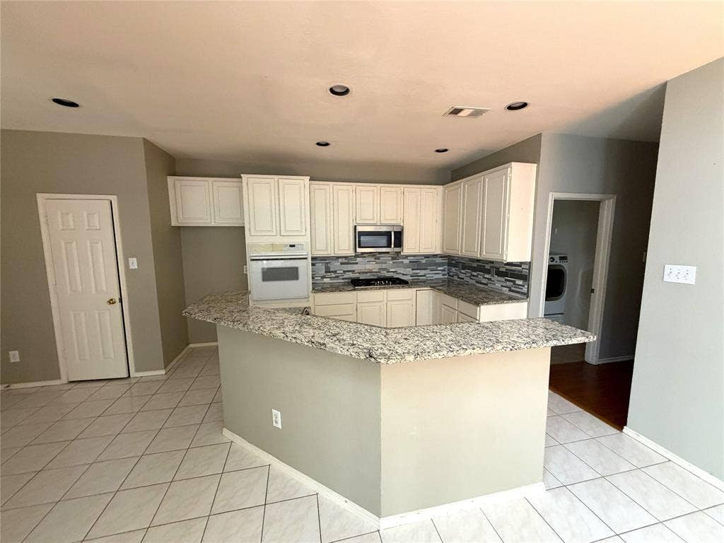 U-shaped kitchen featuring white cabinetry, a built-in oven, and a gas cooktop