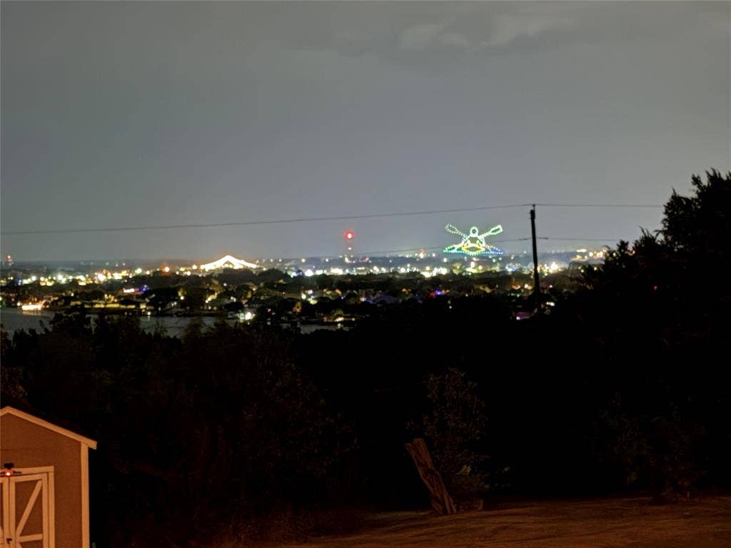 1106 Scenic Drive, Granbury, TX 76048 Elevated nocturnal scenery featuring expansive city lights, distant illuminated structures, and a wooden storage structure
