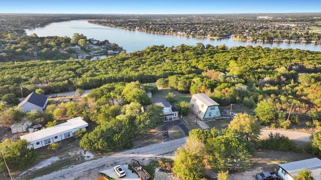 1106 Scenic Drive, Granbury, TX 76048 Aerial perspective featuring significant mature tree coverage, expansive waterfront surroundings, and varied topography