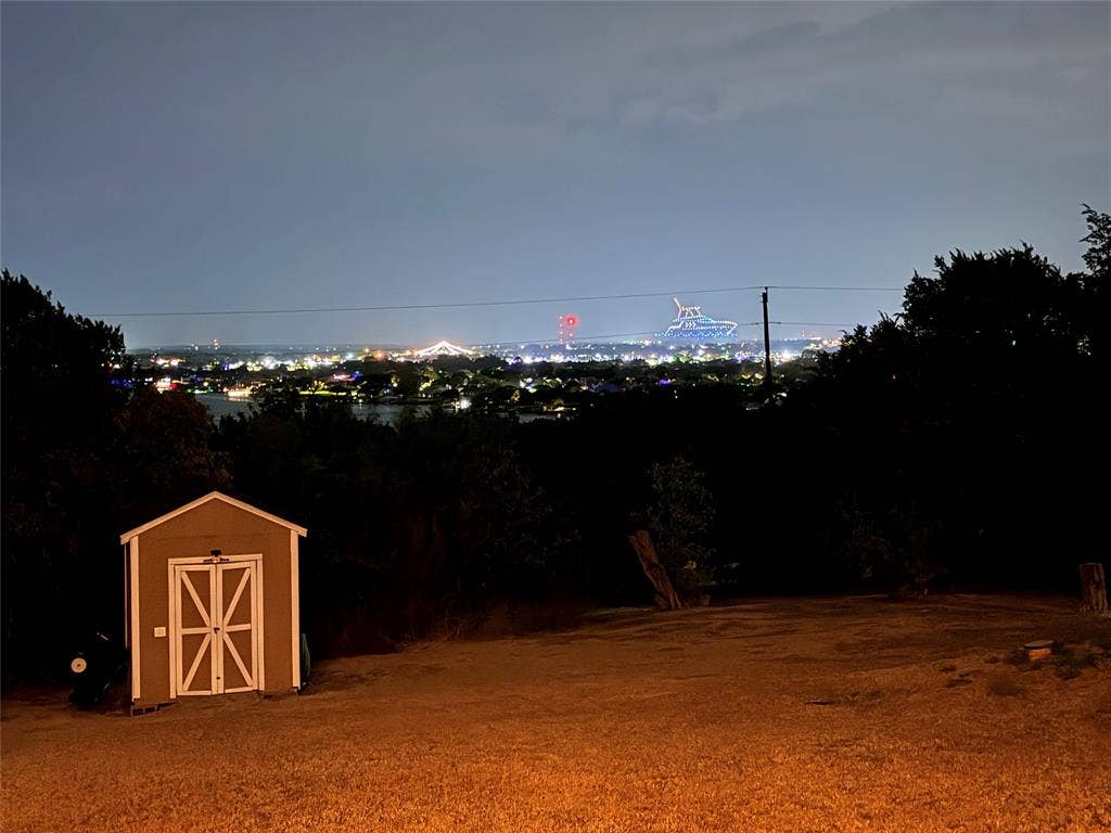 1106 Scenic Drive, Granbury, TX 76048 Expansive elevated lot featuring mature trees, a detached storage shed, and panoramic horizon scenery