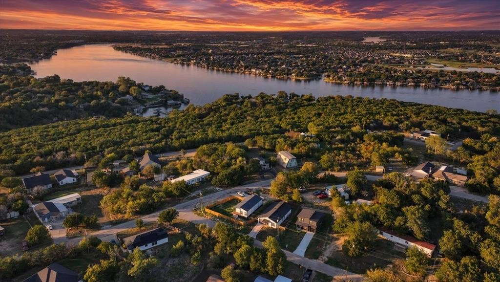 1106 Scenic Drive, Granbury, TX 76048 Aerial perspective featuring a waterfront location, mature canopy of trees, and sunset horizon