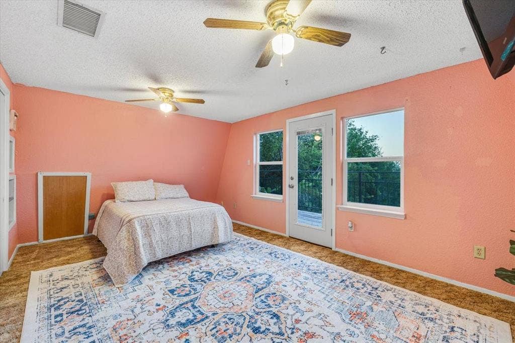 1106 Scenic Drive, Granbury, TX 76048 Interior room featuring dual ceiling fans, two large windows, a glass-paneled exterior door, and built-in storage cabinet