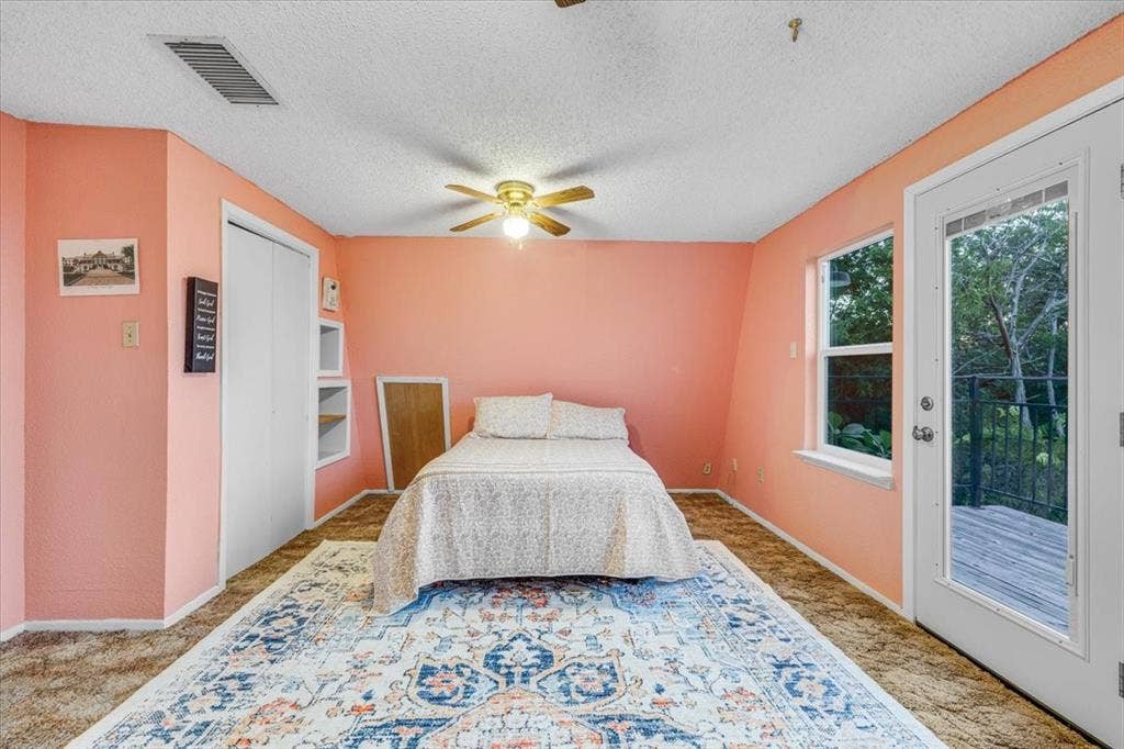 1106 Scenic Drive, Granbury, TX 76048 Room with carpeted flooring, vaulted ceiling, built-in recessed shelving, central ceiling fan, and a glass-paneled exterior door