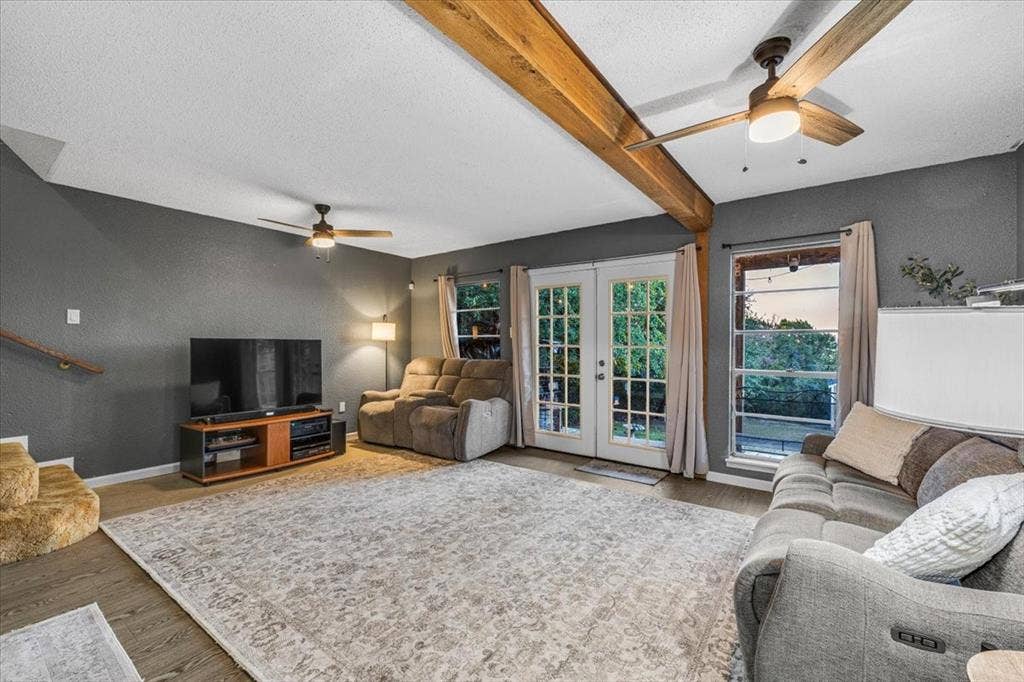 1106 Scenic Drive, Granbury, TX 76048 Living area featuring exposed wood ceiling beams, wood-finish flooring, dual ceiling fans, and French doors providing exterior access