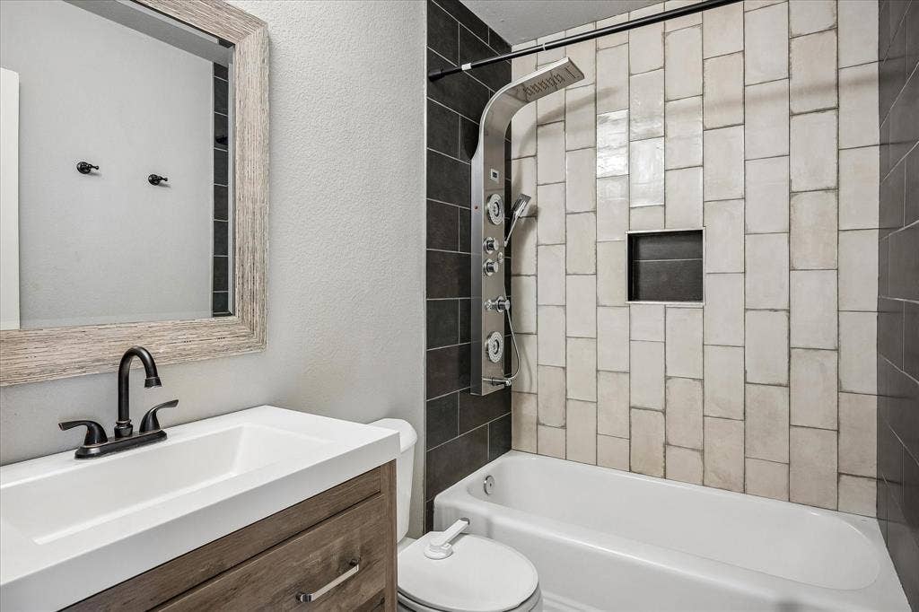 Bathroom featuring a wood-finish vanity, integrated sink, and dark bronze faucet