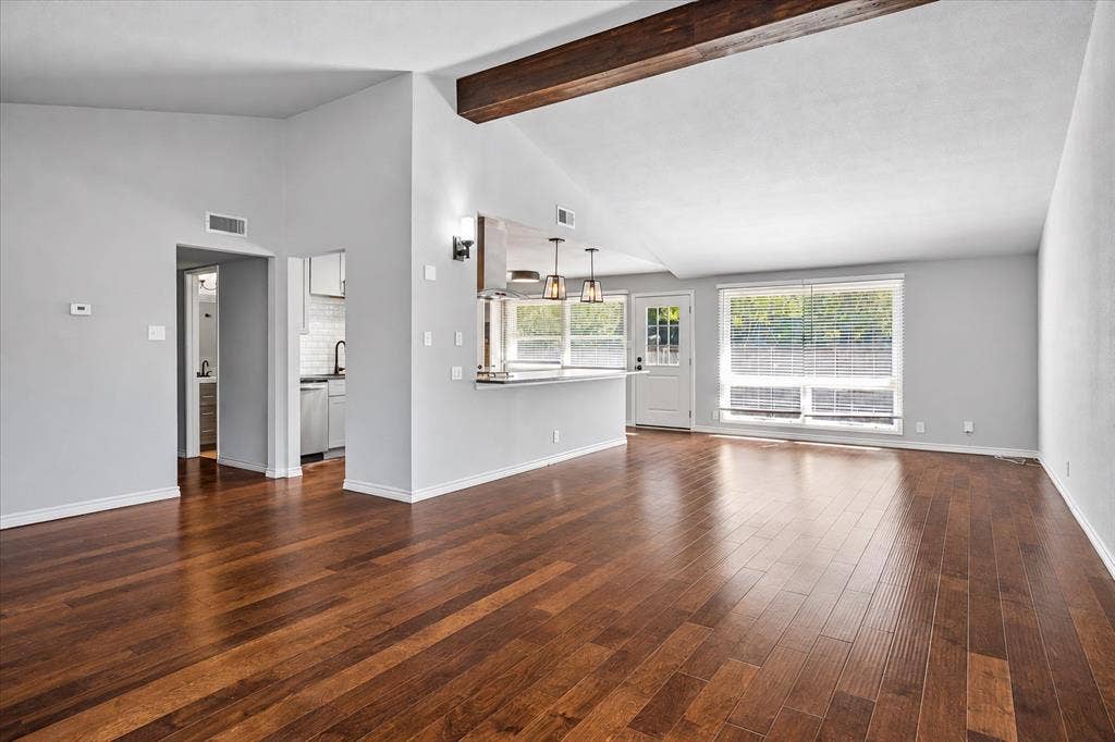 Vaulted ceiling with exposed wood beam, polished wood-finish flooring, and recessed lighting