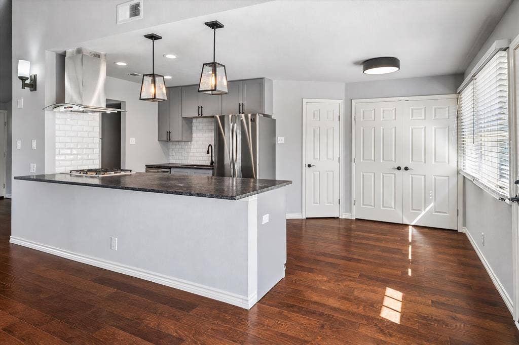 Kitchen featuring a central island, stainless steel appliances, and wood-finish flooring