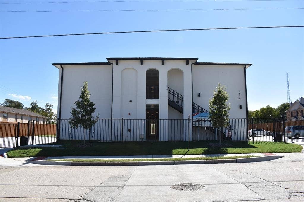 Stucco exterior with a two-story design featuring a central arched entryway