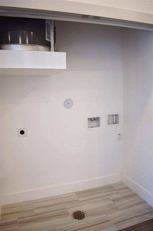 Dedicated utility area featuring white walls, baseboards, and wood-finish tile flooring with a central drain