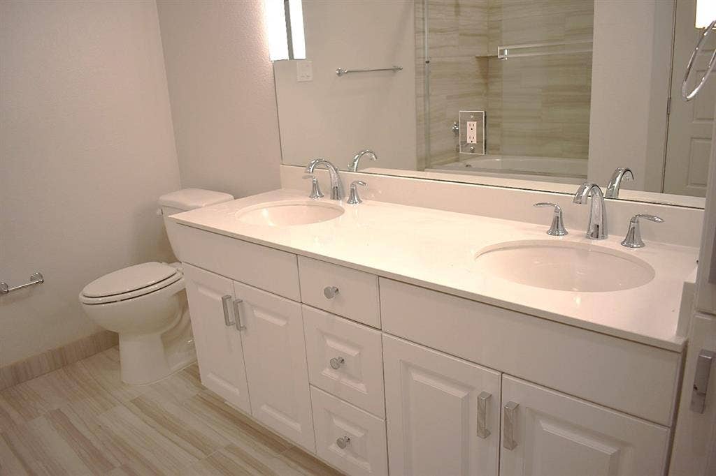Dual vanity with light-toned countertop, integrated sinks, and polished chrome fixtures