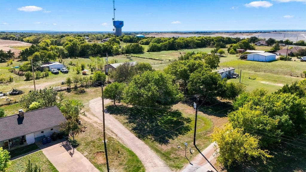 1320 Apple Lane, Midlothian, TX 76065 Aerial perspective featuring expansive acreage, mature tree canopy, gravel drive access, and a multi-structure site layout