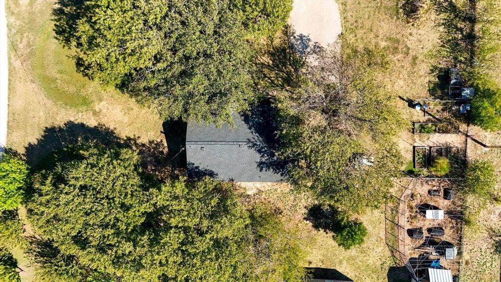 1320 Apple Lane, Midlothian, TX 76065 Aerial perspective featuring a shingled roofline, mature trees, open grounds, and a fenced garden area