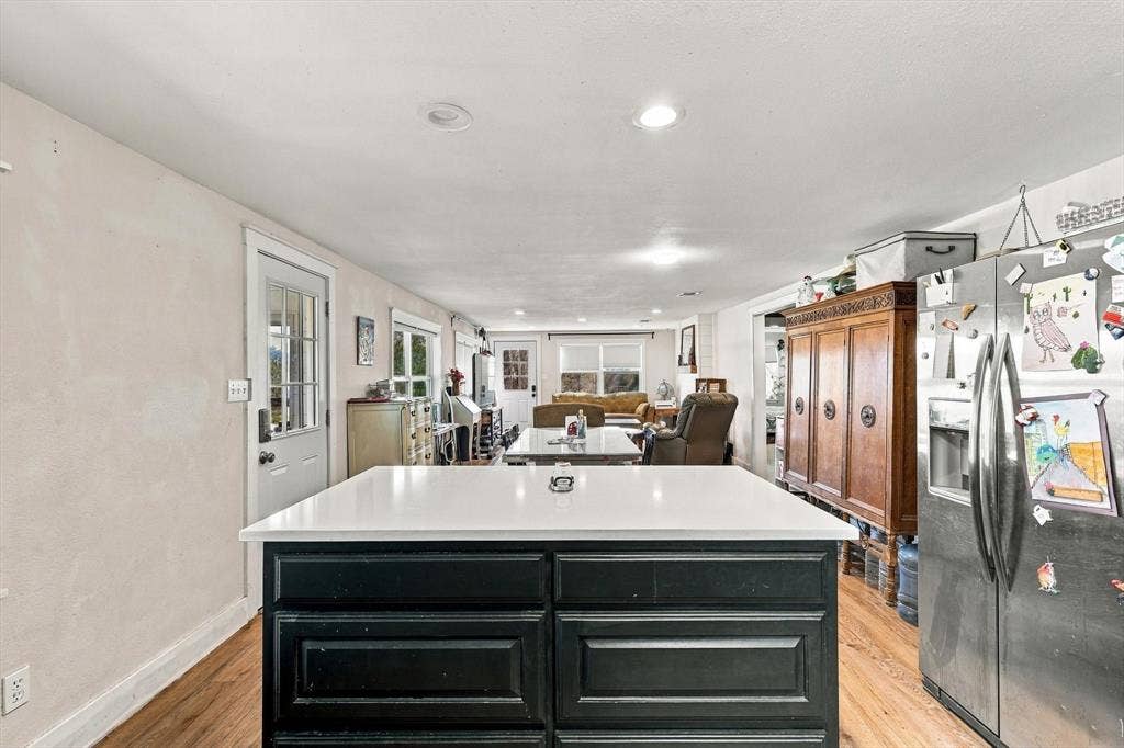 1320 Apple Lane, Midlothian, TX 76065 Kitchen island featuring a solid-surface countertop and dark cabinetry, stainless steel refrigerator, recessed lighting, and wood-finish flooring