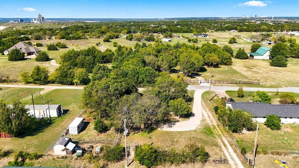1320 Apple Lane, Midlothian, TX 76065 Expansive parcel featuring mature trees, a gravel driveway, perimeter fencing, and open acreage