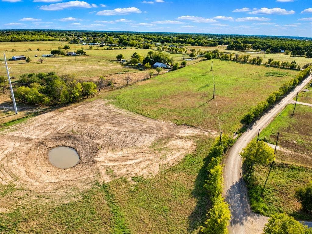 7697 County Road 4094, Scurry, TX 75158 Expansive rural acreage featuring a natural pond, extensive open pasture, mature trees, and frontage on a gravel road