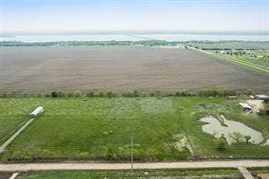 Lot 3 Bozek Lane, Ennis, TX 75119 Expansive land parcel featuring a large cultivated field, a pond, and a gravel road leading to structures